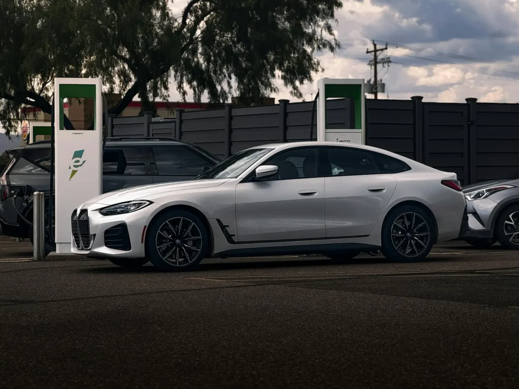 A modern electric car charging at a public EV station, showcasing a sleek design with a focus on sustainability and green technology. The vehicle is powered by clean energy, highlighting the future of transportation