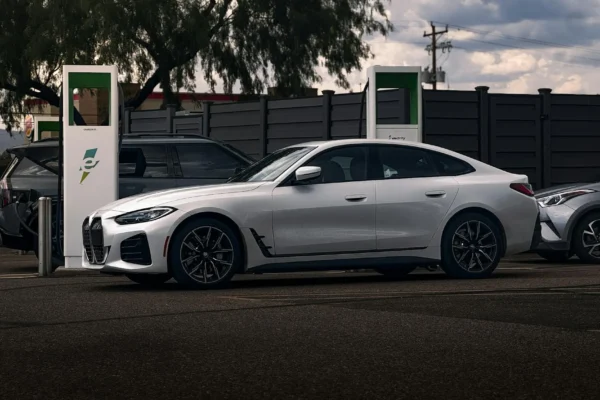 A modern electric car charging at a public EV station, showcasing a sleek design with a focus on sustainability and green technology. The vehicle is powered by clean energy, highlighting the future of transportation